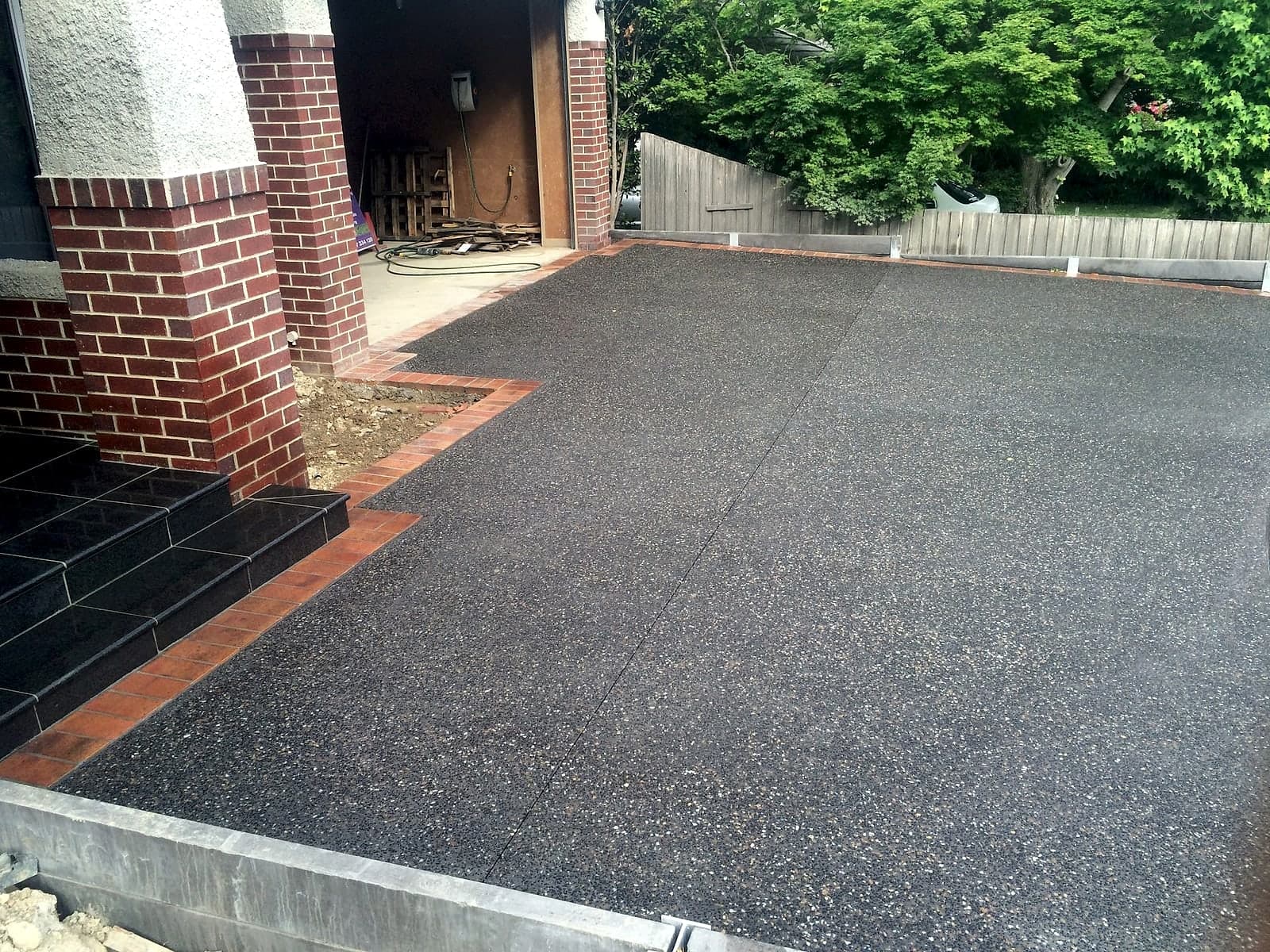 Charcoal aggregate with brick border by Cam Wells Paving